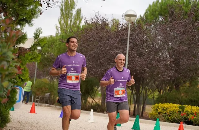 Dos corredores con la camiseta morada de la carrera en 2025