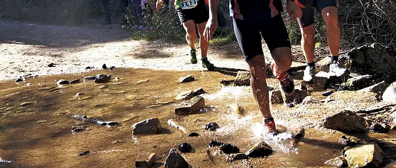 Corredores cruzando un arroyo en la Vuelta a La Jarosa