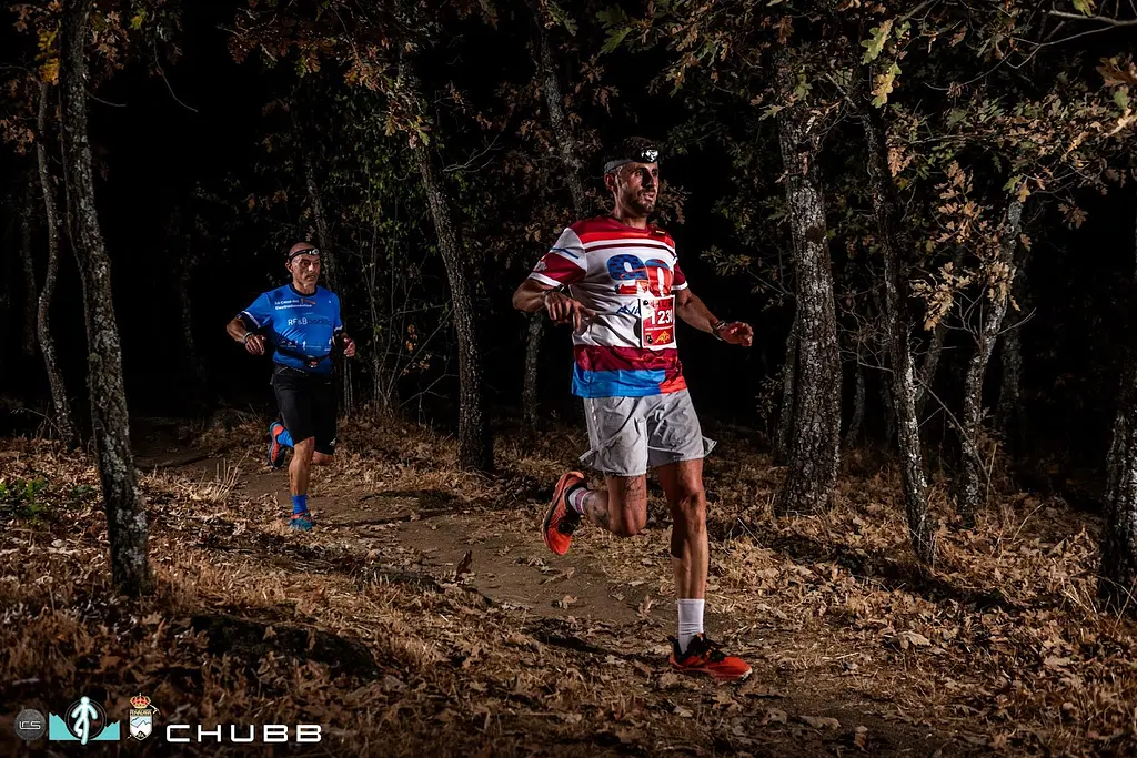 Runners with head torches on a path through the oak woods during the Cross Nocturno de Navacerrada